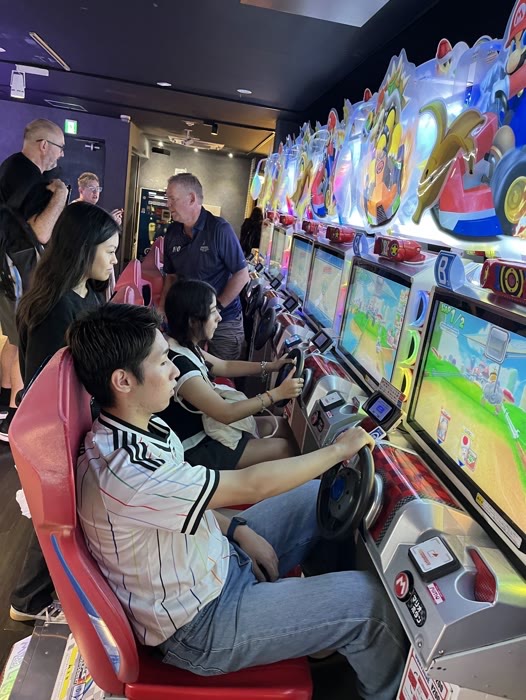 Guests racing side by side on Mario Kart cabinets in an Akihabara arcade
