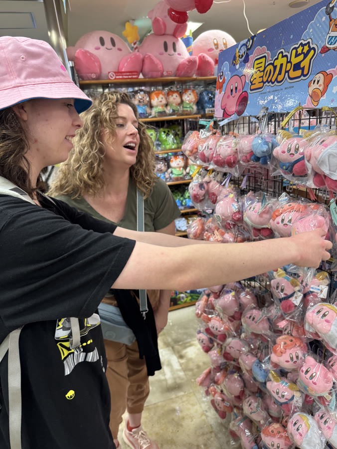 A guest laughing in a wall of plush toys in an Akihabara shop